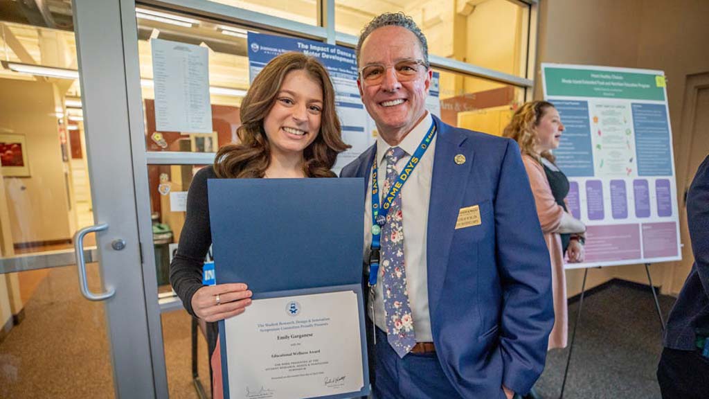 One of the twelve winners at the Symposium, Emily Garganese, smiling with President Greene with their award