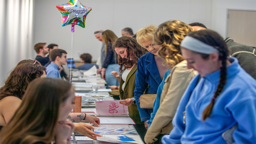 Students showing design portfolios to attendees