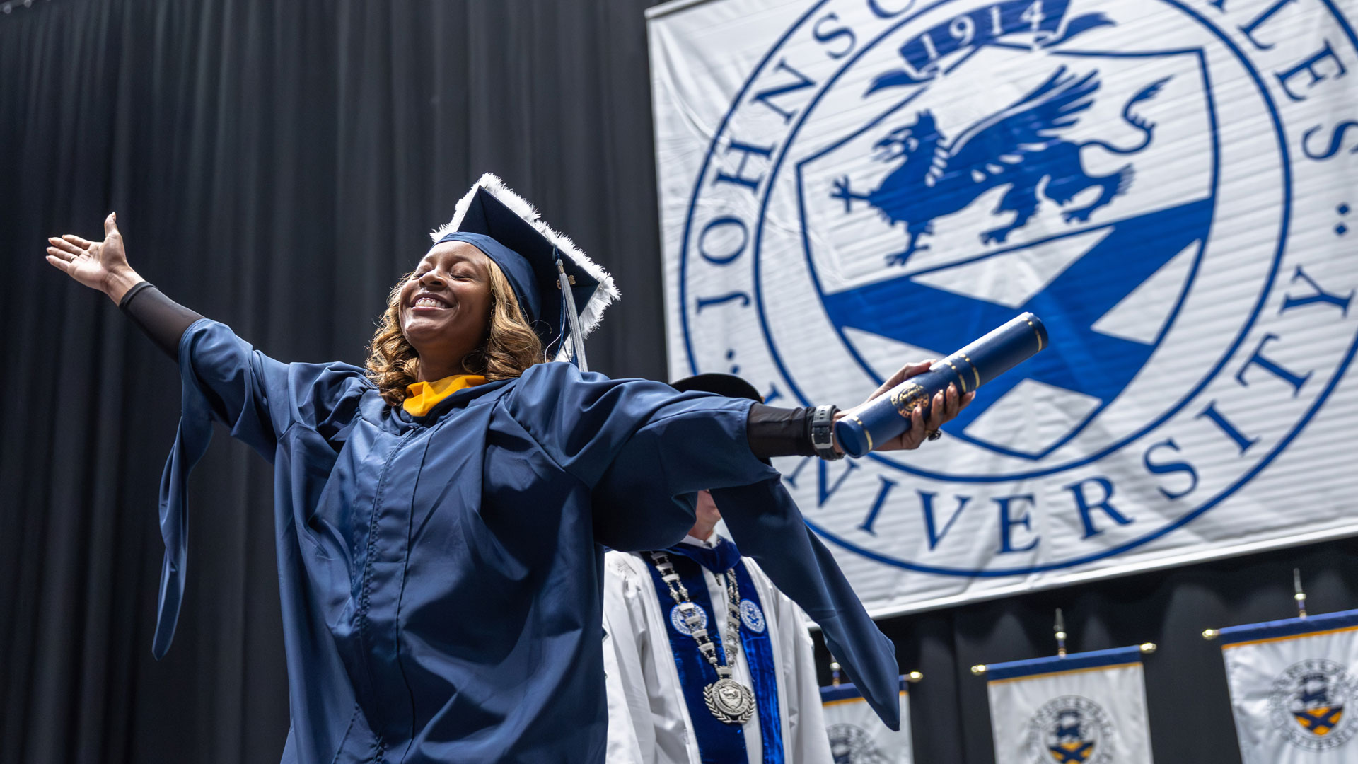 Charlotte grad with her arms outspread and a smile on her face.