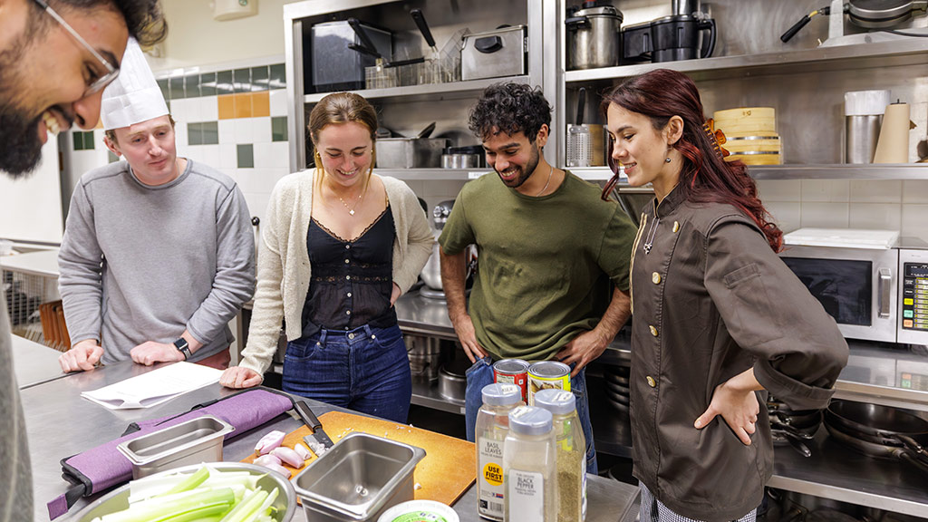 Brown medical students smile at ingredients in a culinary lab