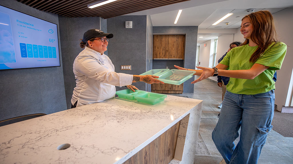 Photo of smiling woman handing eco box to student